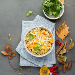 The perfect vegetarian dinner. Bulgur with pumpkin, carrots, spices (ginger, cinnamon, pepper, cardamom), honey and cilantro. A autumn gray concrete background for you.  Flat lay, top view