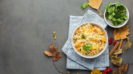 The perfect vegetarian dinner. Bulgur with pumpkin, carrots, spices (ginger, cinnamon, pepper, cardamom), honey and cilantro. A autumn gray concrete background for you.  Flat lay, top view