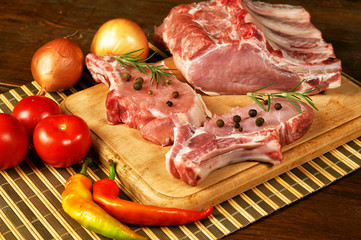 Raw steak , chops, meat with spices and vegetables on wooden table