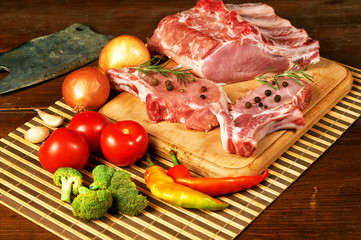 Raw steak , chops, meat with spices and vegetables on wooden table