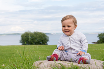 The boy is sitting on a stone with a view of the beautiful coast