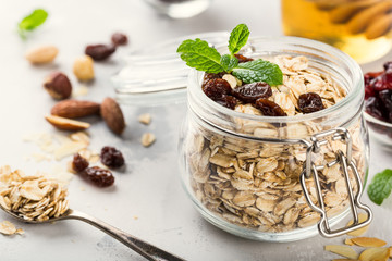 Oat flakes in glass jar with honey, raisins and nuts. Healthy breakfast concept.