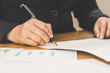 Close up business woman signing terms of agreement documents on her desk, signing concept