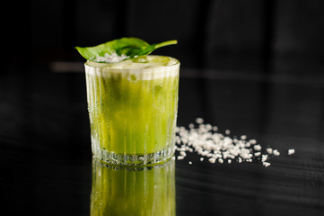 Glass of fresh green alcoholic cocktail decorated with basil leaf