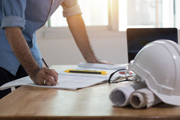 Enginee or architect  drawing and writing on plan paper on desk, architect and working concept.