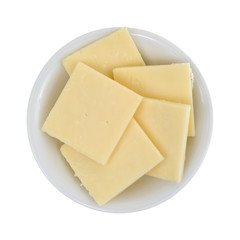 Top view of a small bowl filled with sharp cheddar cheese square slices isolated on a white background.