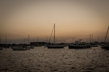 Fototapeta premium Sail boats docked with sea ocean background. Maritime boats docked with sunset colorful clouds.