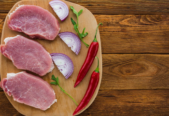 Raw meat steaks on wooden board