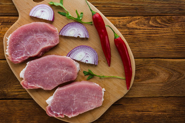 Raw meat steaks on wooden board