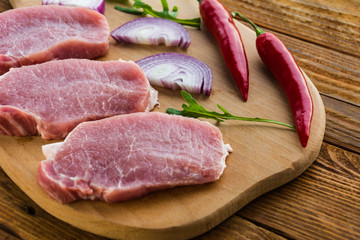 Raw meat steaks on wooden board