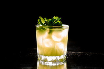 Glass of fresh alcoholic drink with ice decorated with parsley leaves