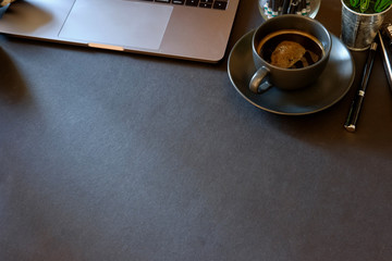 Dark Desk with laptop, eye glasses, books, pen and a cup of coffee. Top view with copy space.