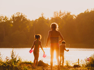 Three children play on the beach in sunset light