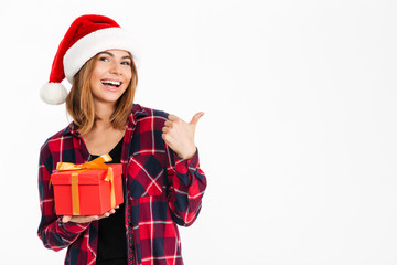 Happy brunette woman in shirt and christmas hat holding gift