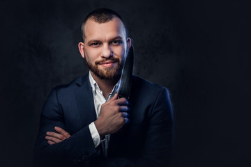 A man in a suit holds a Chef's knife.