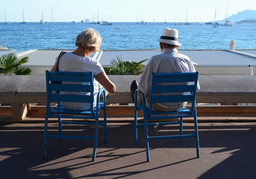 Cannes, France - September 11, 2015. A senior couple sitting on blue chairs and reads magazines in Cannes