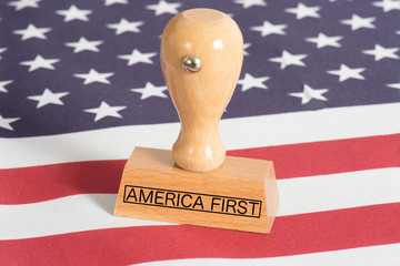 Flagge der USA und ein Stempel mit dem Aufdruck America First