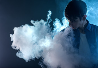 vaper exhales cloud of smoke on blue background