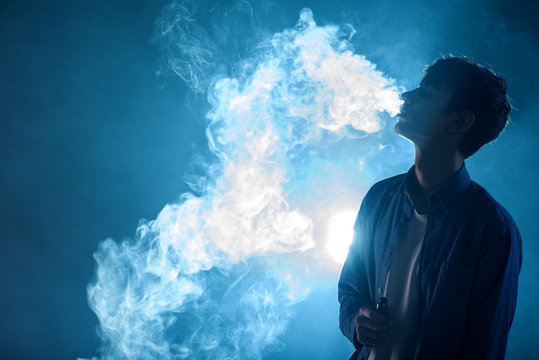 man smoking vape and exhales cloud of smoke