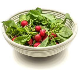 Whole red radish with fresh green leaves in rattan bowl isolated on white background.