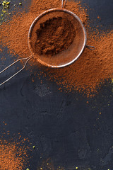 Cocoa powder in a sieve over black slate background