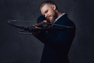 A man dressed in a suit holds crossbow.
