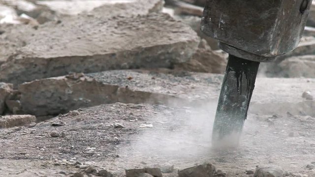 Professional electric tools for breaking the concrete cover. Clay digger in the process of work: close-up. Perforator for the destruction of concrete. Cracks on the floor from the work of a jackhammer