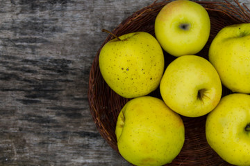 Ripe green apples in a basket on rustic wooden table