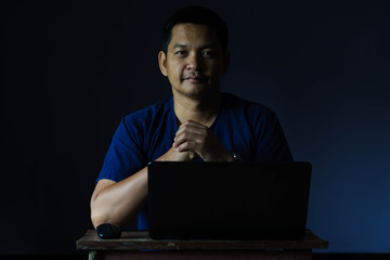 Portrait of asian man play laptop in dark room , Low key style.