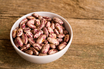 Сolorful kidney beans in the bowl on a wooden table
