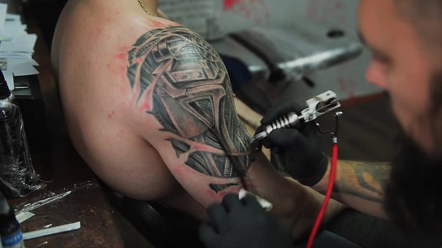 the process of creating a tattoo on the back of a man. Professional tattoo.