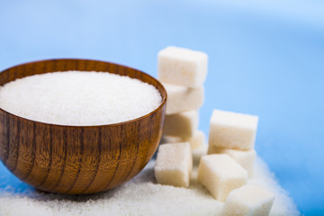 Fototapeta na wymiar Sugar in a wooden bowl and cubes of sugar