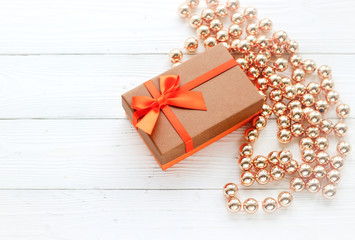 holiday decorations, gift box and beads on white wood background, top view