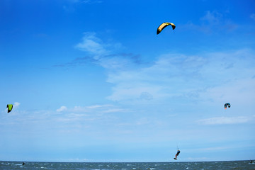 Man riding a kite surfing on the waves in the summer.