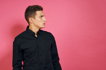 Obraz premium man in a black shirt looking away on a pink background