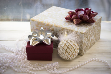 Fototapeta na wymiar Colorful gift boxes wrapped in paper and christmas decoration on white sill against window