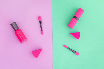 Cosmetics on colorful background. Pink nail polish and lipstick on pink and mint background top view