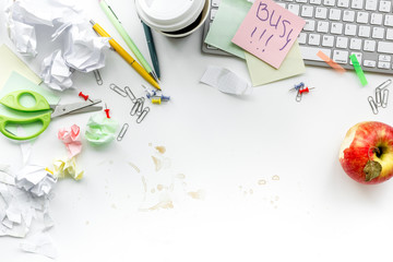 Deadline in office. Sticker Busy on desk covered with crumpled paper and stationery on white background top view copyspace