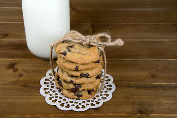chocolate chip cookie stack with string bow on lace doily with white milk in glass bottle
