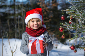 Cute little boy with christmas gift im winter forest