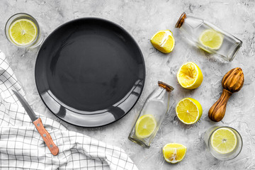 Fresh homemade lemonade. Lemons, juicer, glass for beverage on grey stone background top view mockup