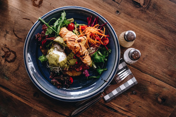 Top view of croissant bacon and egg benedict with avocado sauce, serve on wooden table for breakfast