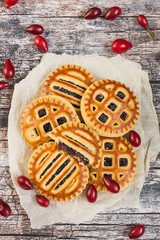 Sweet homemade baking. A biscuit filled with jam from fresh fruits dogwood on an old wooden table.