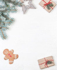 Christmas frame with gifts, fir tree branches, xmas holiday decorations, festive symbols on white wooden background with copyspace. Christmas composition..