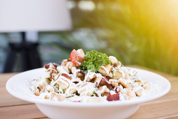 Healthy grilled red meat salad with cheese and croutons. Bacon and lettuce slices in a white plate on a wooden table.