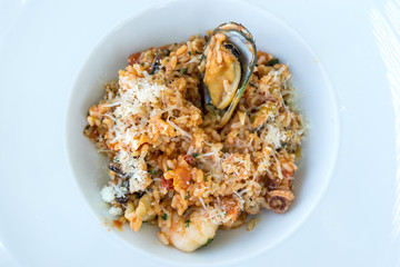 Tasty risotto with Shrimp, fresh herbs vegetables on a white plate