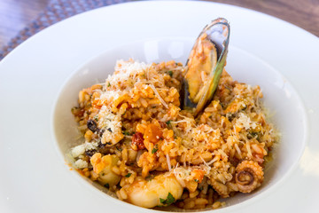 Tasty risotto with Shrimp, fresh herbs vegetables on a white plate