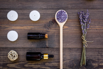 Fototapeta na wymiar Skin care and relax. Cosmetics and aromatherapy concept. Lavender spa salt and oil on dark wooden background top view