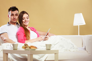Couple reading ebook relaxing at home on sofa.