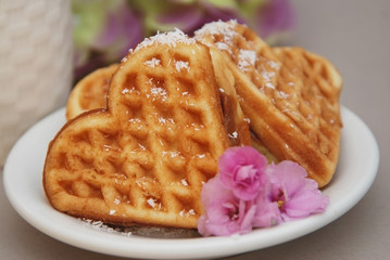 Waffles in White Plate Breakfast Dessert with Pink Flowers. Toned, Isolated. Sweet Heart Shape Cake with Cream. Close Up. Food.
